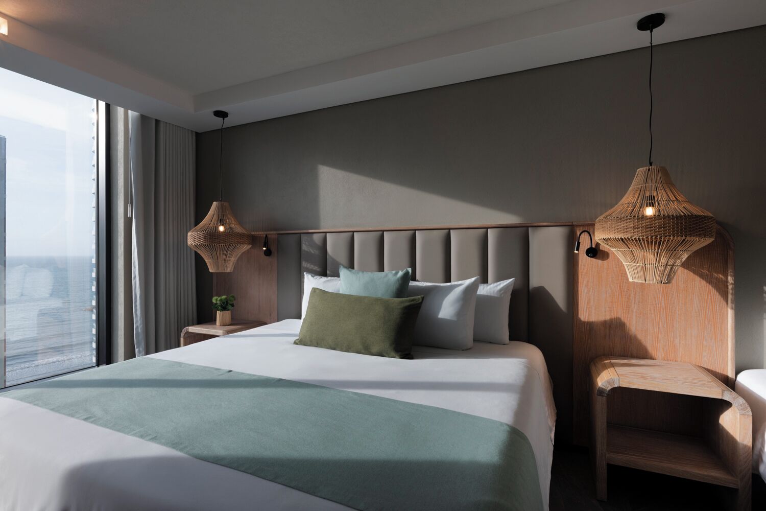 A modern hotel room with a large bed, two bedside tables, a wooden chair, and a large window offering a city view.