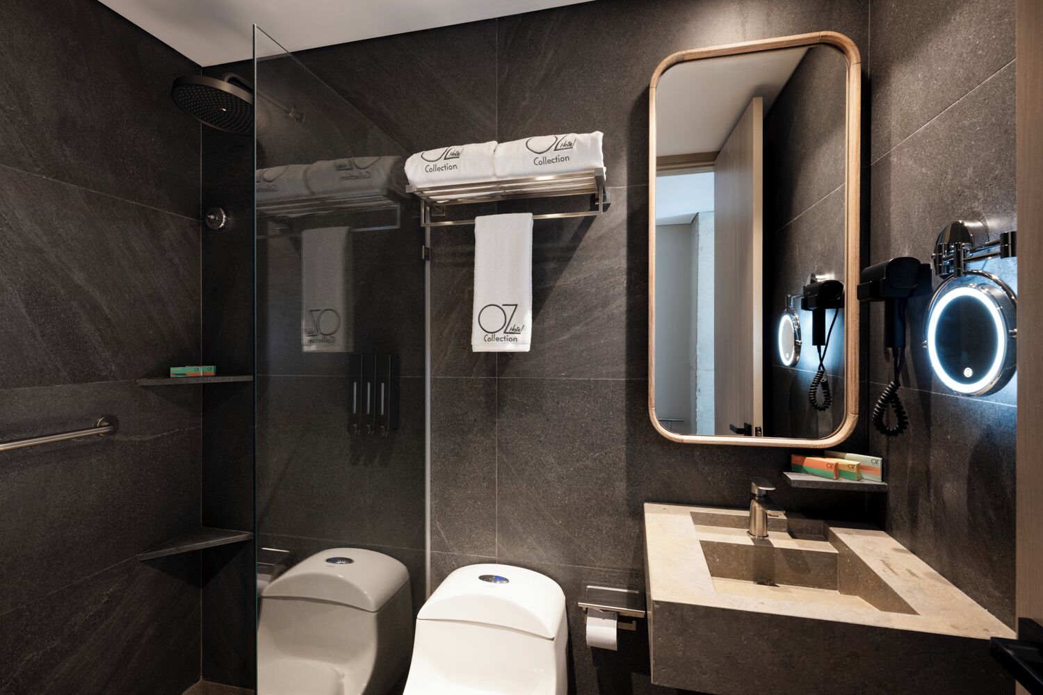 A modern bathroom with a glass-enclosed shower, a toilet, a sink with a mirror, and a towel rack.