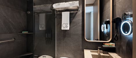 A modern bathroom with a glass-enclosed shower, a toilet, a sink with a mirror, and a towel rack.