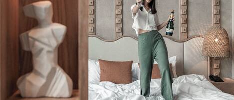 A person standing on a bed in a room with a modern design, including a headboard with vertical lines and a wooden shelf with decorative items.
