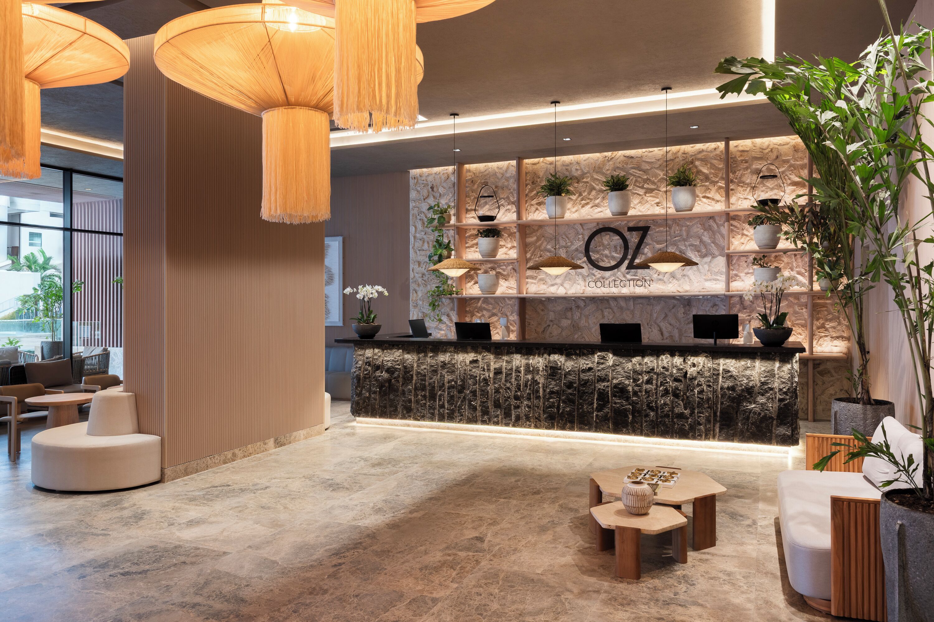 Una moderna zona de recepción con pared de piedra, plantas en macetas y un mostrador de recepción.