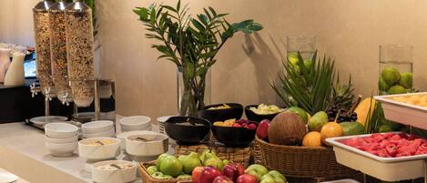 A buffet with various food items and drinks, including fruits, cereals, and beverages.