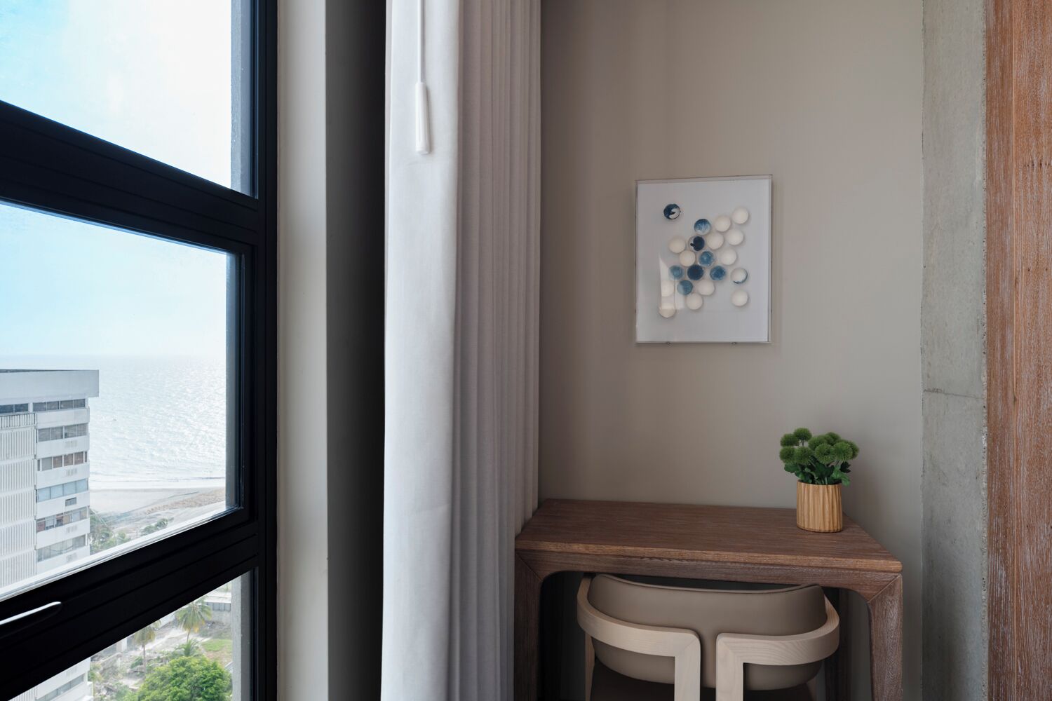 Una habitación en esquina con ventana, escritorio, silla y un cuadro colgado en la pared.