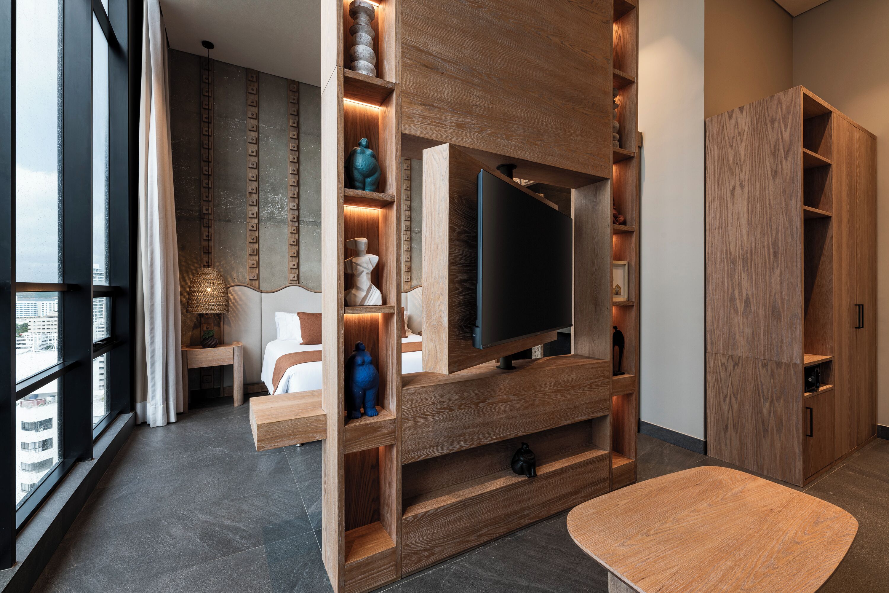 Un salon moderne doté d’un grand téléviseur à écran plat, d’étagères en bois et d’un espace détente.