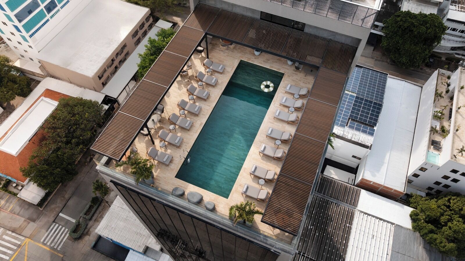 Vista aérea de un área de piscina en la azotea con sillones de descanso y una piscina pequeña.
