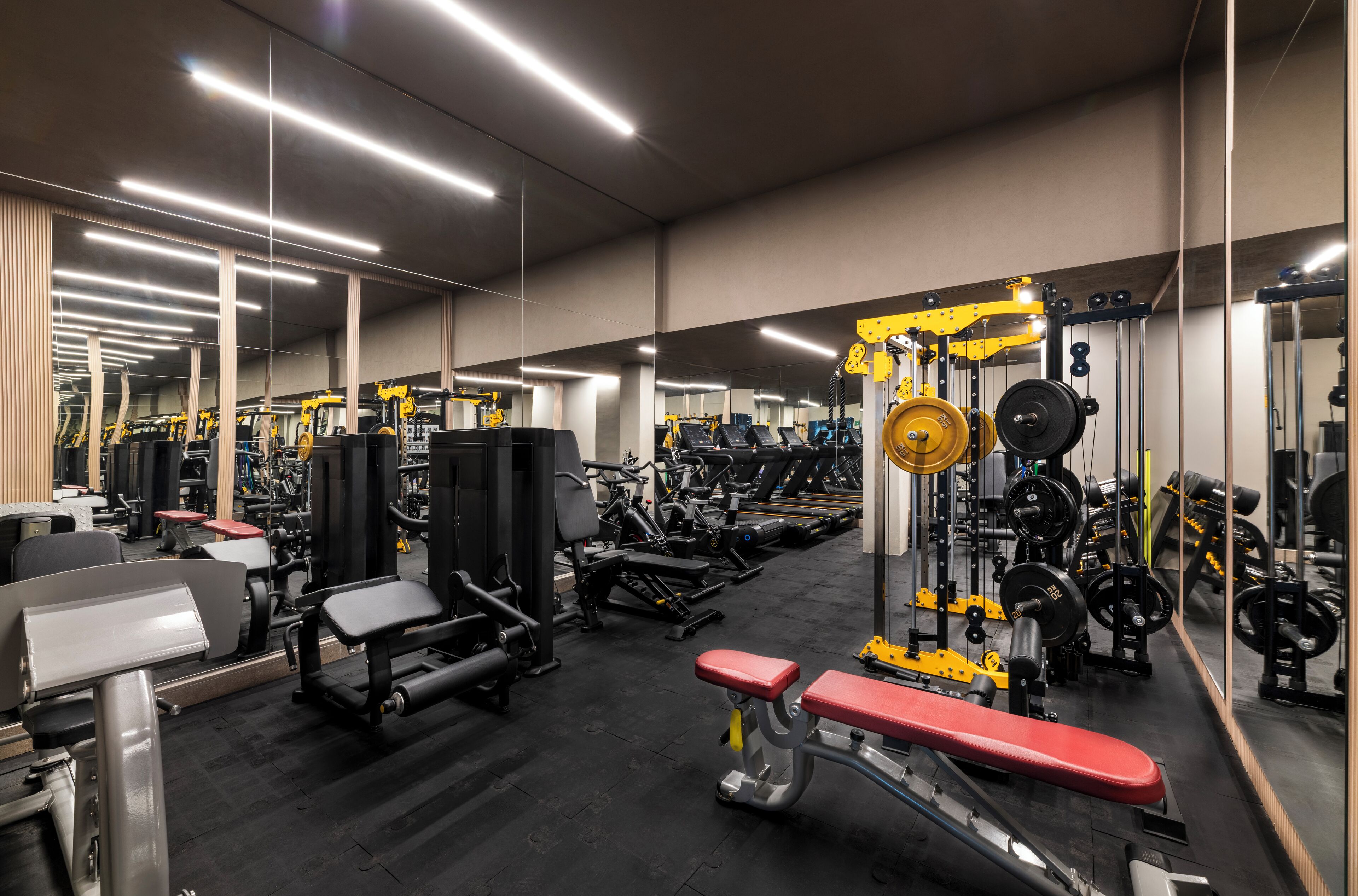 A modern gym with various exercise equipment, mirrors, and ample lighting.