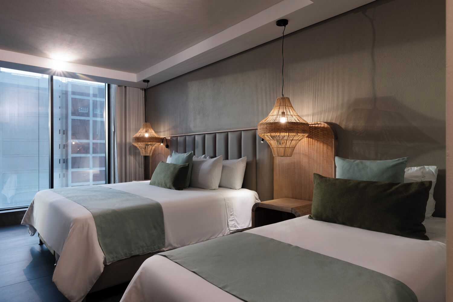 Ein Hotelzimmer mit zwei Betten, einem großen Fenster und zwei Wandlampen.