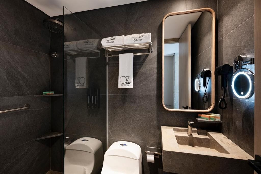 Ein modernes Badezimmer mit einer gläsernen Duschkabine, einem Waschbecken mit Spiegel und einer Toilette.