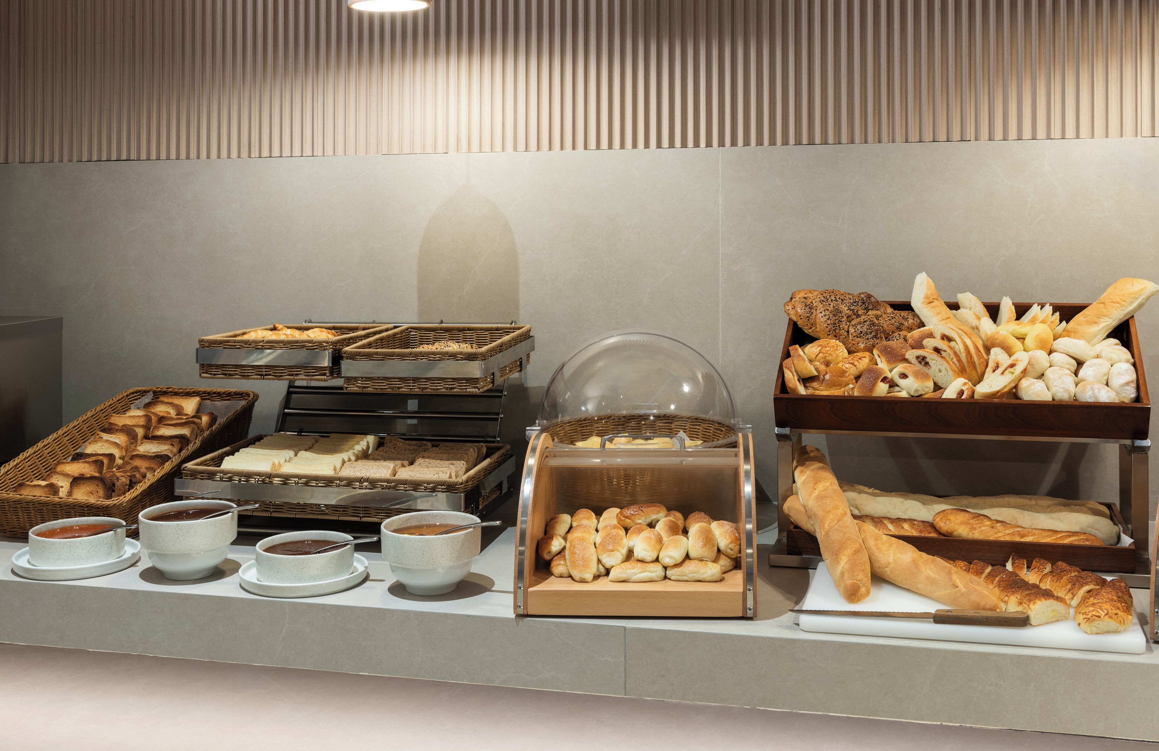 Un bufé con panes, pasteles y recipientes para sopa.