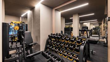 Ett gym med olika typer av träningsutrustning, inklusive hantlar och styrketräningsmaskiner.