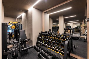 Et fitnesscenter med forskellig træningsudstyr, herunder håndvægte og styrkemaskiner.