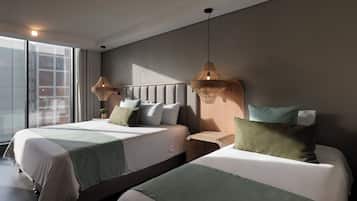 Una habitación de hotel moderna con dos camas, un ventanal grande y vista a la ciudad.