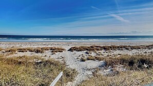 Ein Strand mit einem Sandweg, der zum Meer führt.