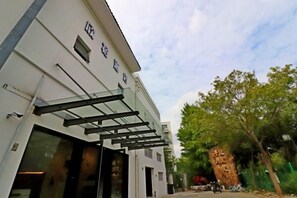A building with a modern facade, large glass windows, and a metal awning. - Xinyu Hotel (Shanghai)