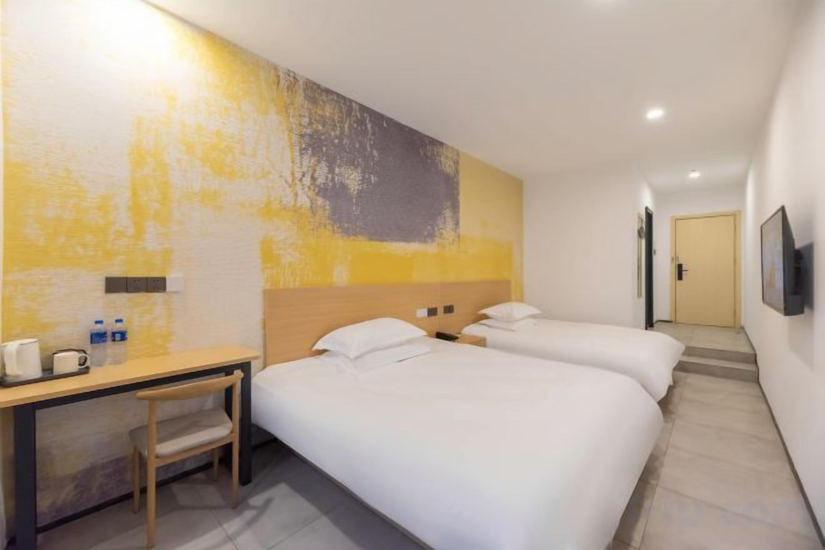 A hotel room with two beds, a desk, and a chair.
