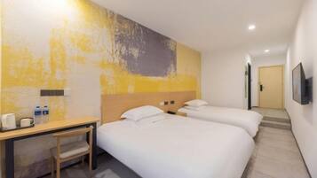 A hotel room with two beds, a desk, and a chair.