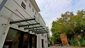 Un bâtiment moderne doté d’une entrée en verre et d’un grand rocher orné de caractères chinois.