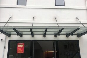 A building entrance with a glass awning and a red sign. - Xinyu Hotel (Shanghai)