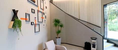 A modern interior with a staircase, a sofa, and a potted plant.