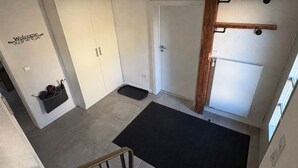Una habitación con armario, puerta, felpudo negro y estructura de madera con vigas.