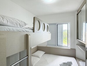 Un dormitorio con literas, una cama individual, una ventana con persianas y un espejo en la pared.