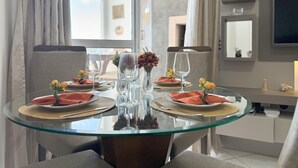 A dining area with a glass table, grey upholstered chairs, and a modern interior design. - Resid. Clube Mar Grosso-Laguna - LAG604 (Laguna)
