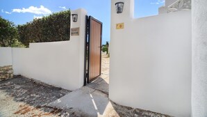 A gated entrance with a wooden door, a white wall with a number sign, and a hedge in the background. - Villa Mirador - Charming 3 Bedroom Spanish Finca (Teulada)