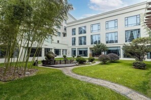 Un edificio moderno con un patio, un sendero y abundante vegetación.