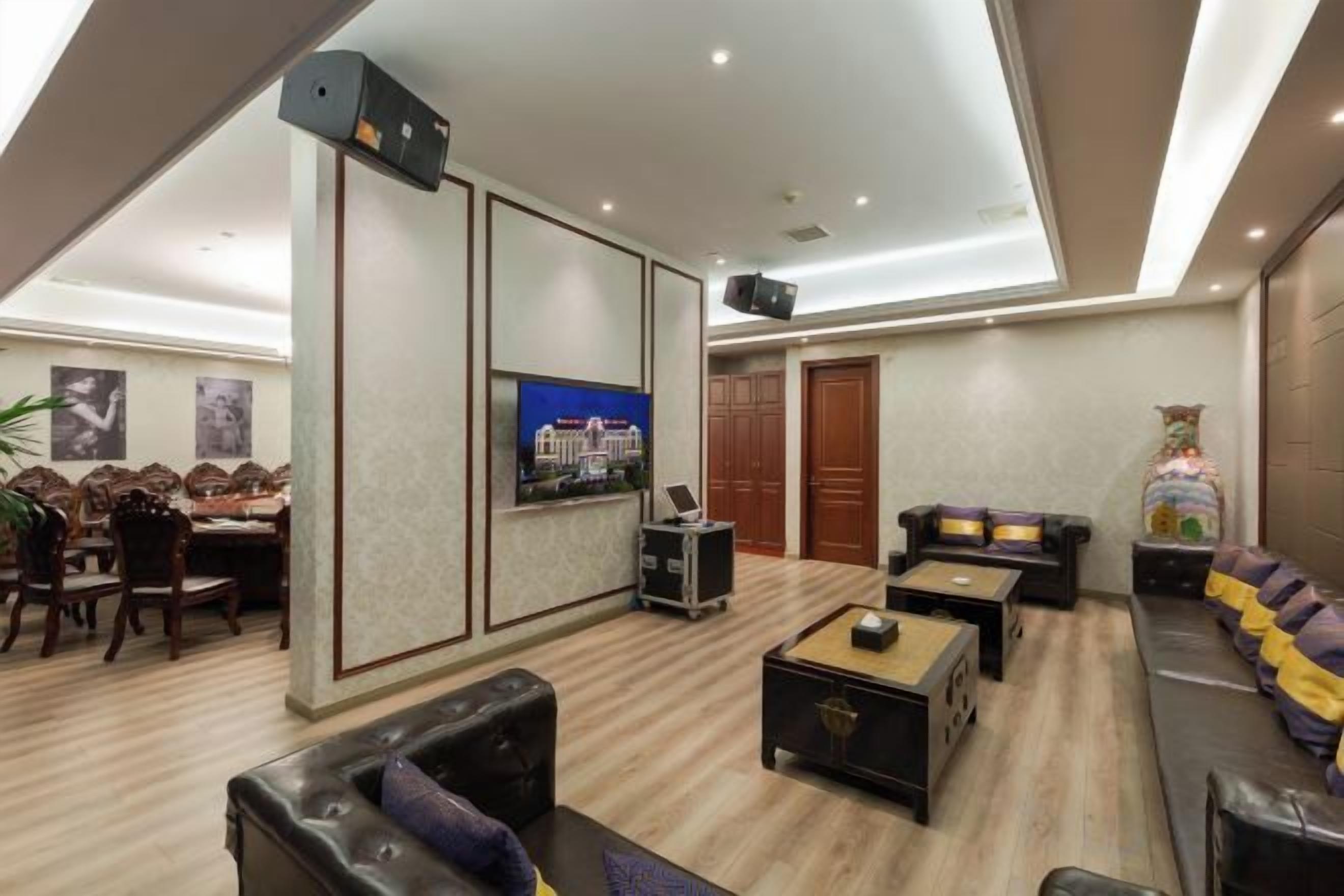 A spacious living area with a flat-screen TV, a sofa, a coffee table, and a dining area with chairs and a table.