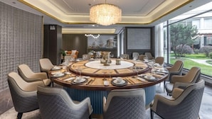 Comedor moderno con una mesa redonda dispuesta para ocho personas, rodeada de sillas tapizadas.