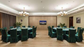 A conference room with round tables, chairs, and a television screen.