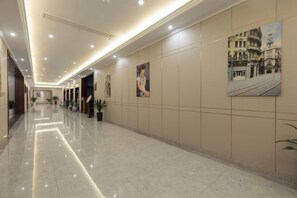 A hotel corridor with a polished floor, wall-mounted artwork, and recessed lighting. - Xiang Yuan Hotel (Cixi)