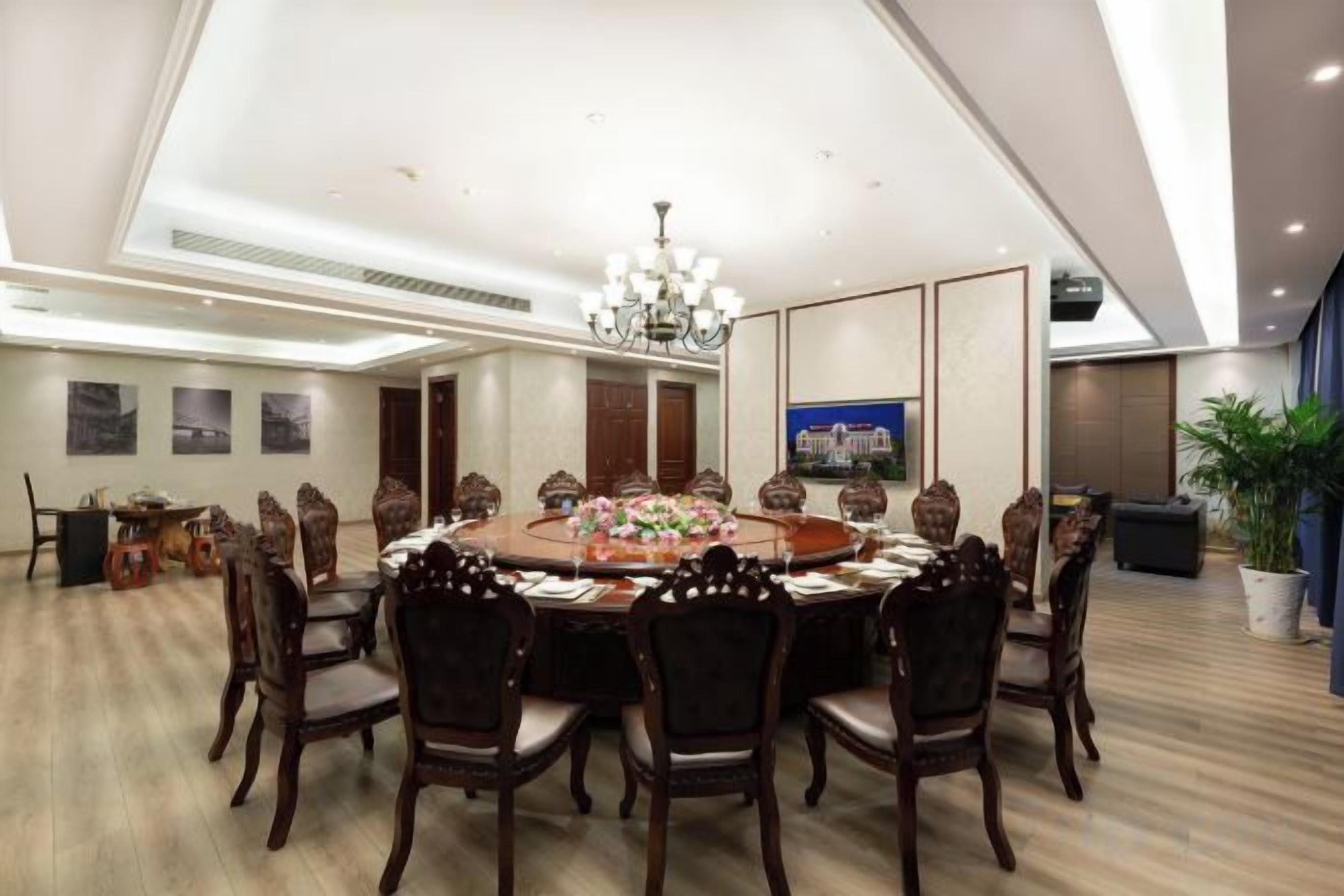 A conference room with a round table, chairs, and a chandelier.