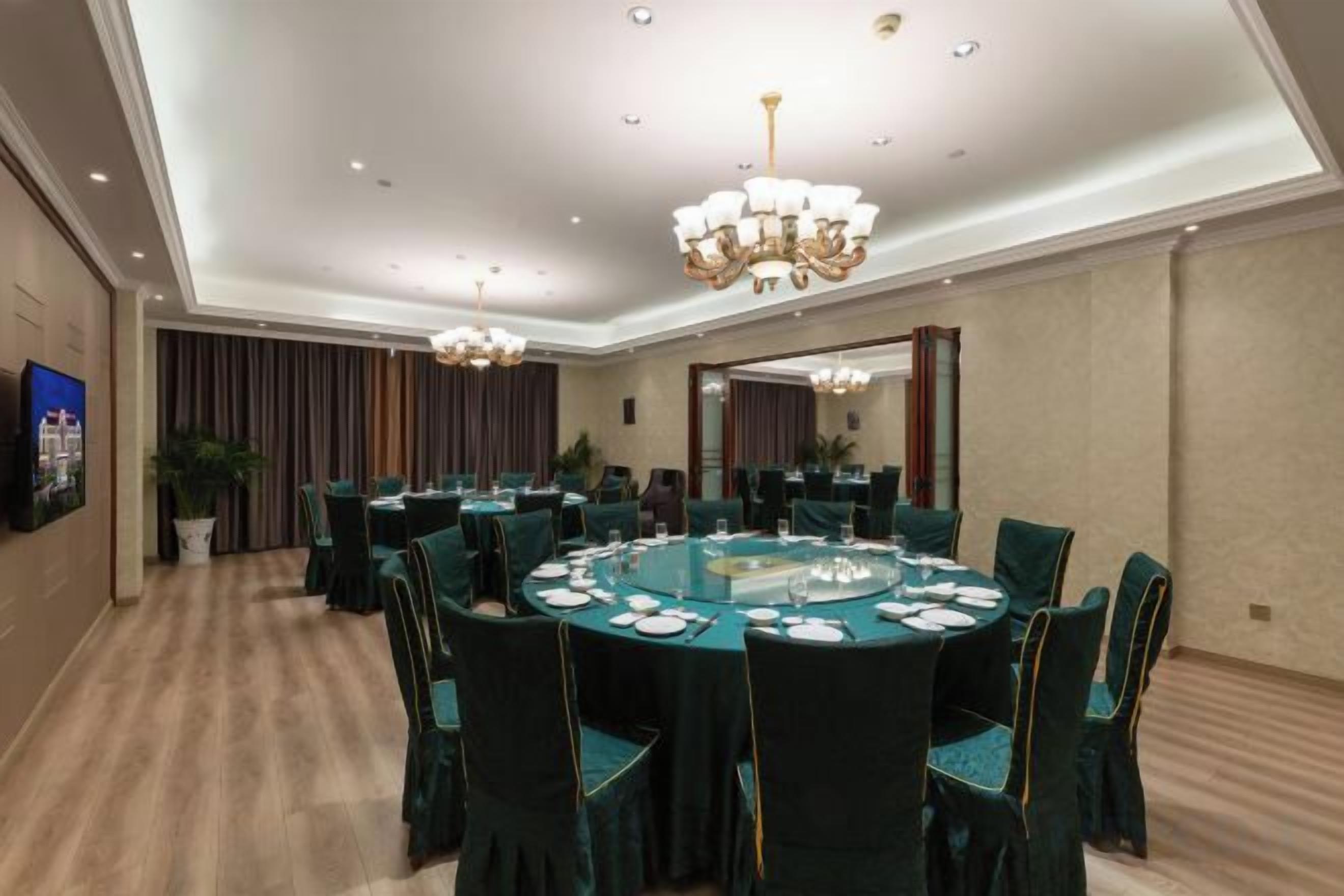 Uma sala de conferências com mesas redondas, cadeiras e um candelabro.