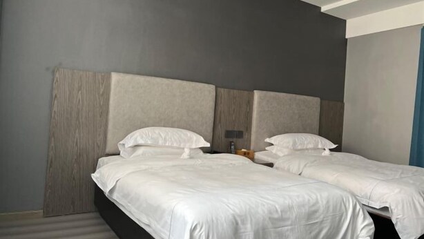 A double room with two beds, a wooden headboard, a nightstand, and a wall-mounted light fixture. - Xiang Yuan Hotel (Cixi)