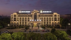 Un hotel moderno con fachada simétrica, entrada iluminada y un atrio central.