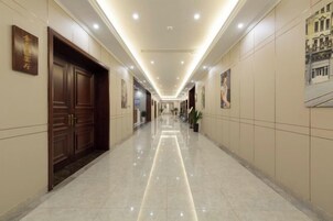 Un pasillo de hotel con puerta de madera, una obra de arte enmarcada y piso pulido.