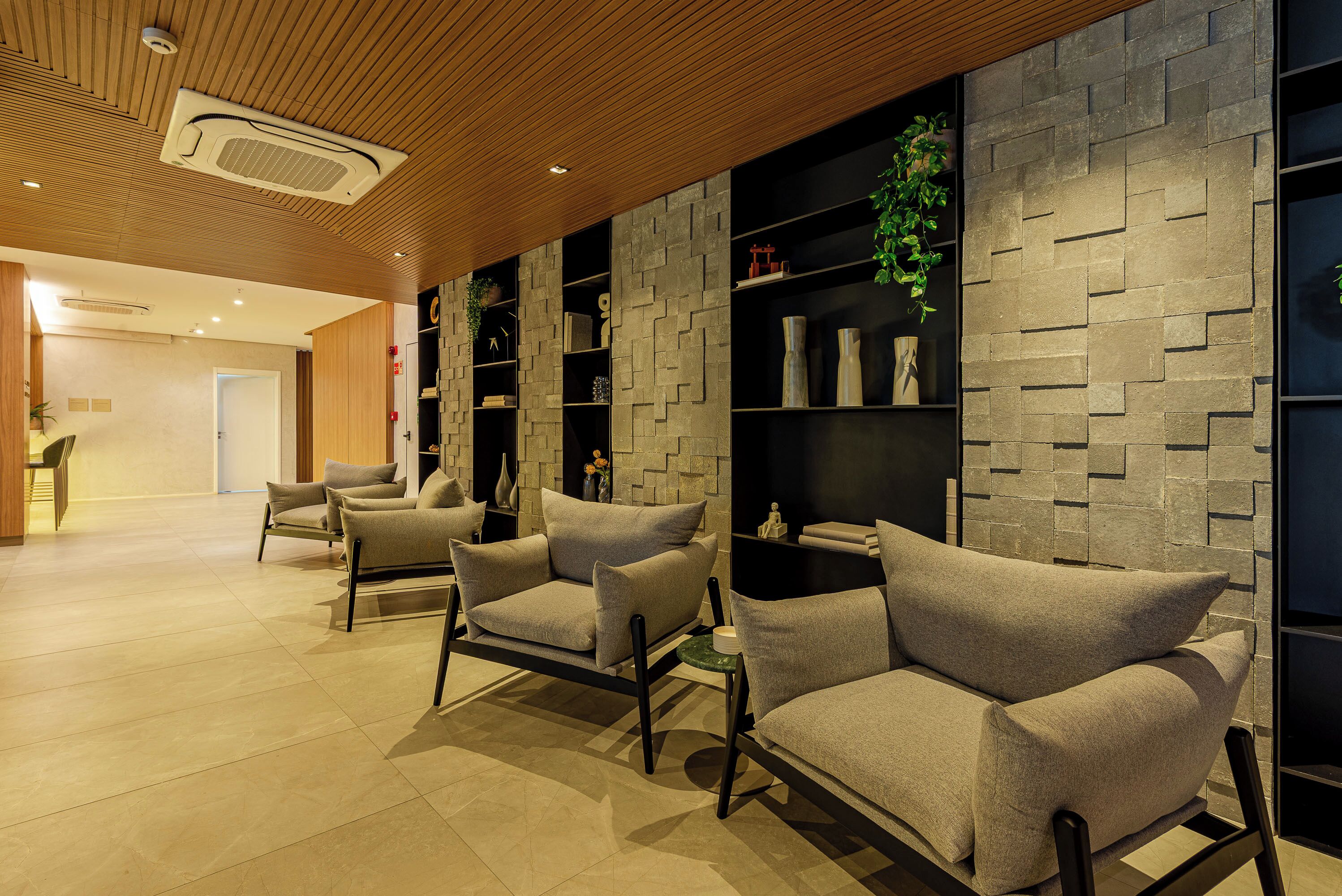 A modern lobby with two sofas, a small table, and a stone wall.