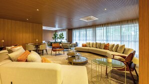 A modern living room with a large sofa, a coffee table, and a dining area with chairs and a table.