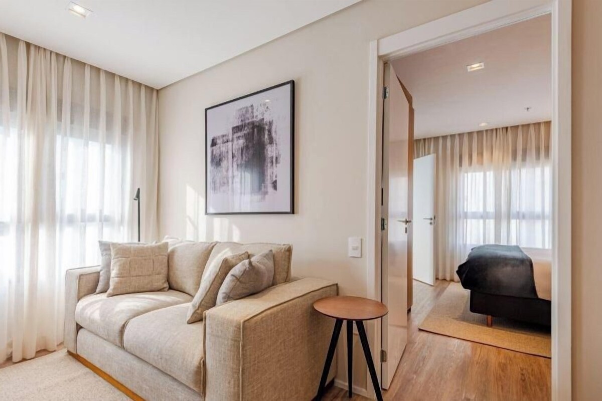 Una sala de estar moderna con un sofá color beige, una mesita redonda y una silla negra.