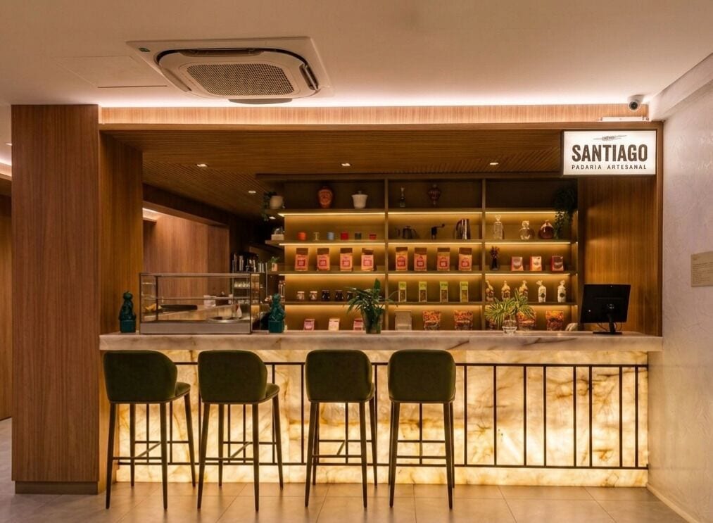 A bar area with a wooden counter, multiple stools, and a sign indicating a local artisan bakery.