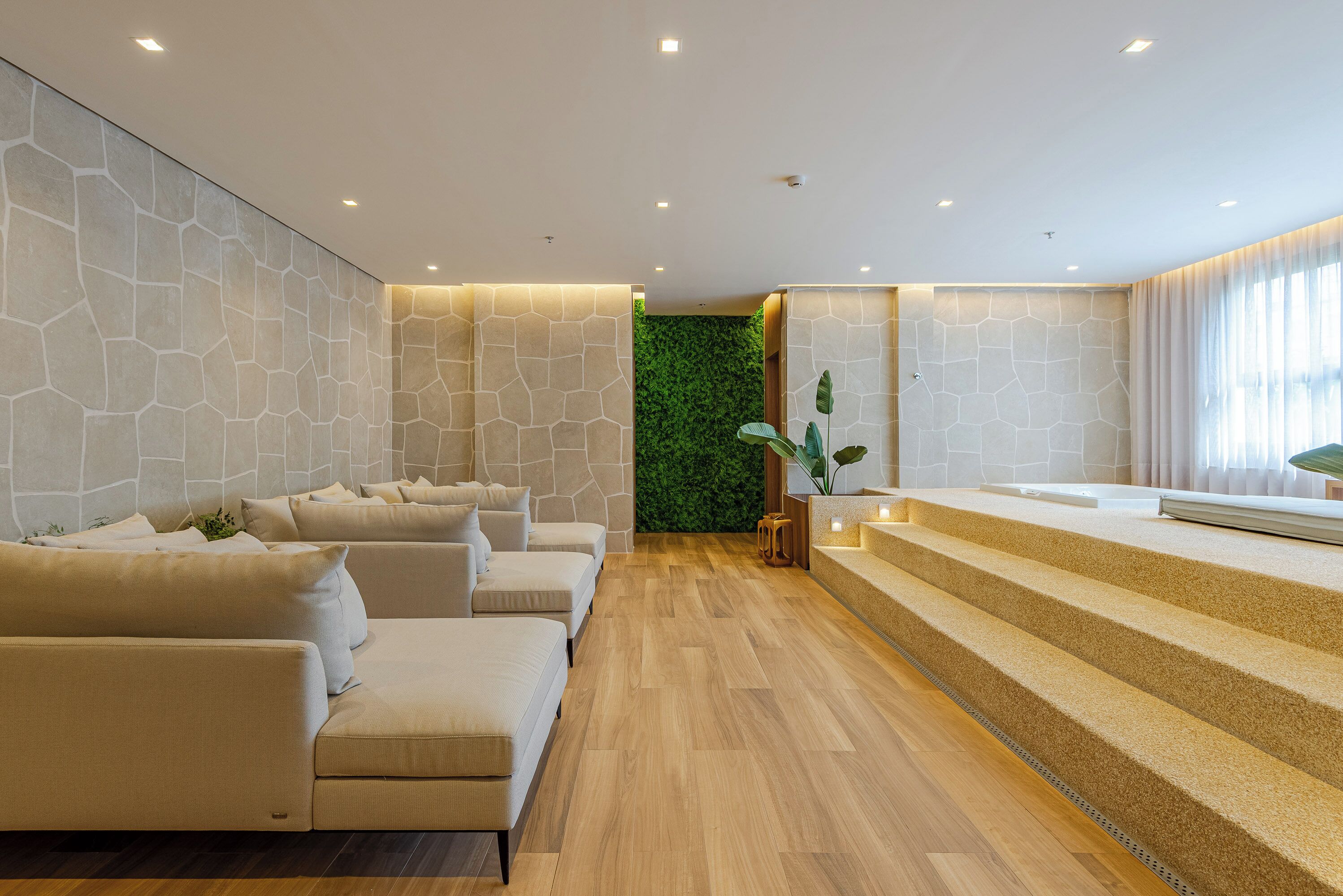 Eine moderne Hotelhalle mit einer Rezeption, einer grünen Wand und einer Sitzecke mit Sofas.