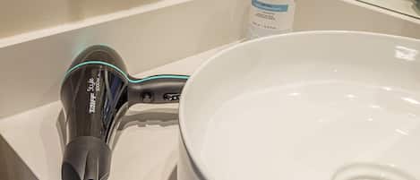 A bathroom sink with a hairdryer and a bottle of Radisson body wash.