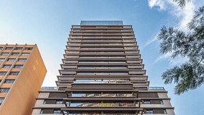 A modern high-rise building with multiple balconies, large windows, and a sign indicating 'Huis Introit'.