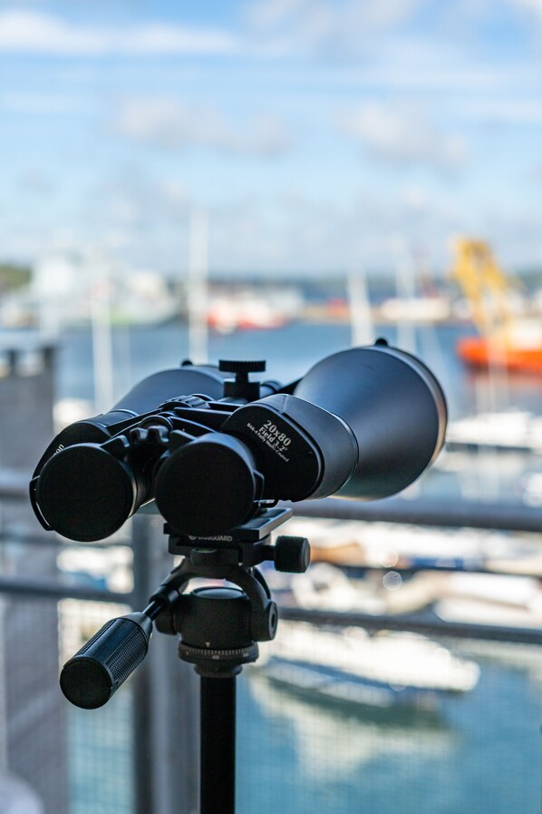 A telescope on a tripod with a marina and boats in the background. - 10 Maritime House (Falmouth)