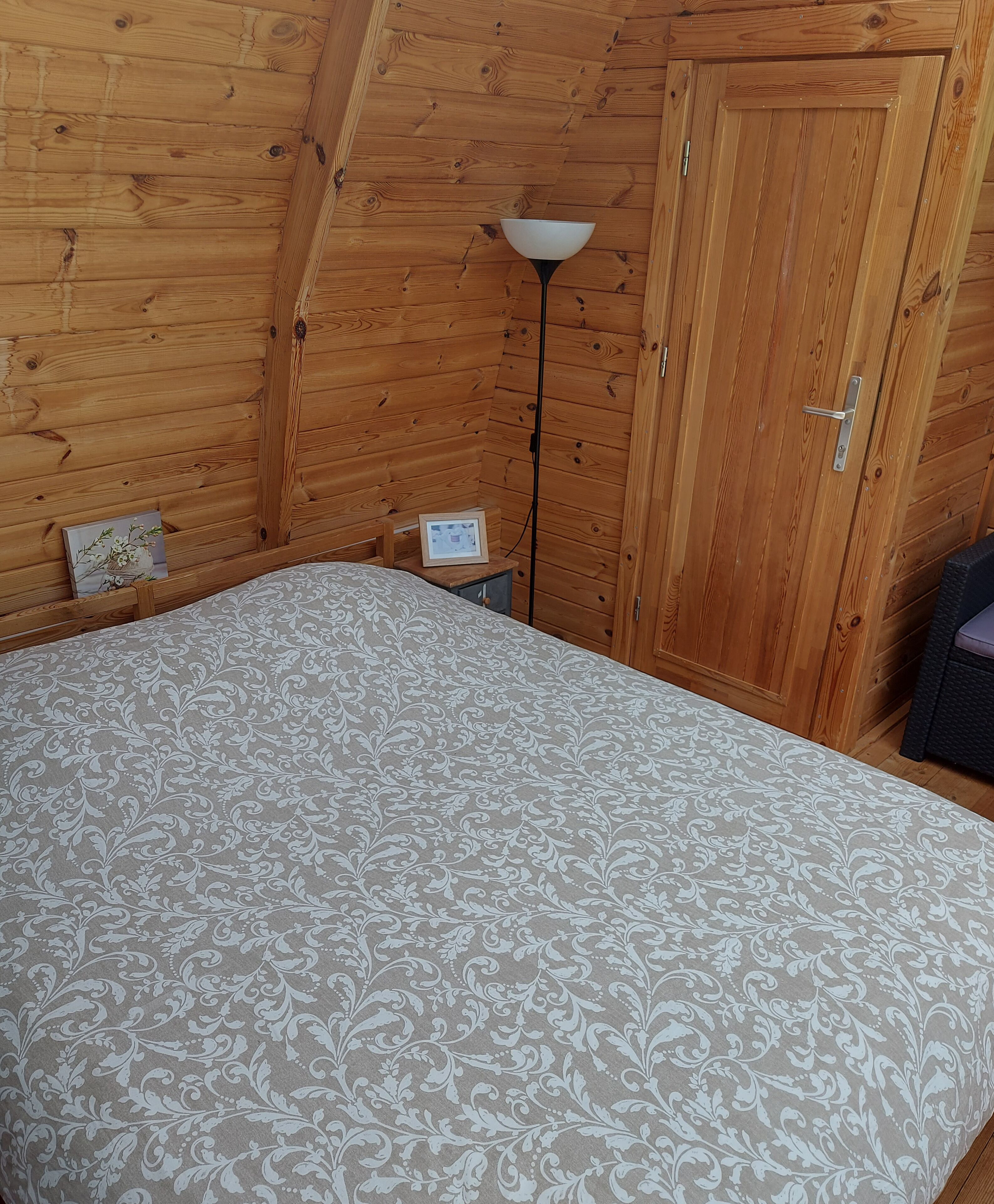 A bedroom with a bed, a nightstand, a lamp, and a door.