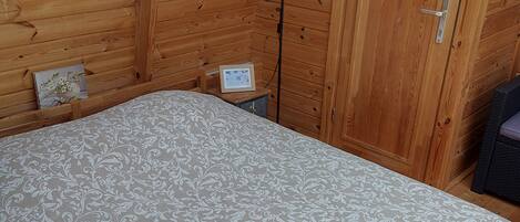 A bedroom with a bed, a nightstand, a lamp, and a door.
