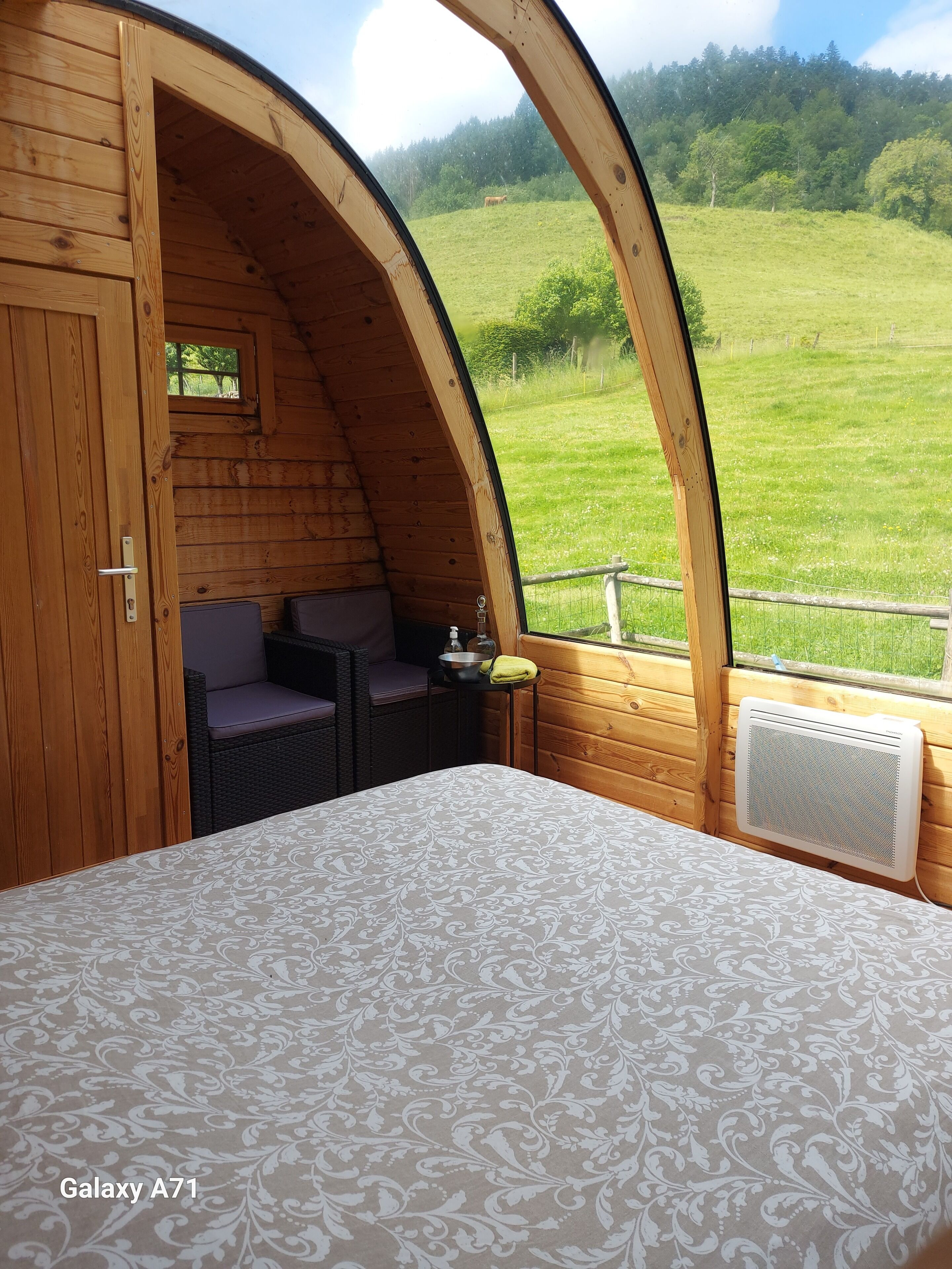 A cozy, circular wooden room with a bed, a small table, and a chair.