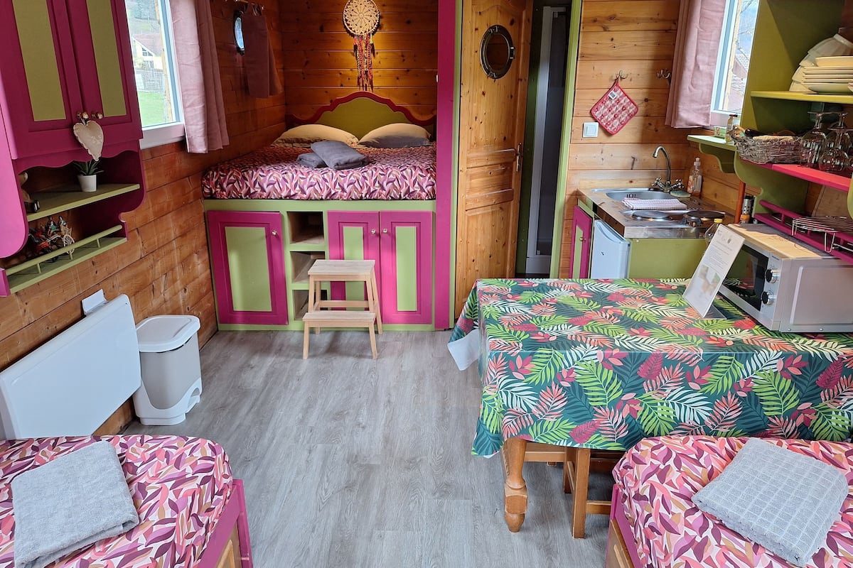 Una habitación acogedora tipo cabaña con literas, una mesita y una kitchenette.