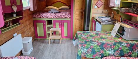 A cozy cabin-style room with a bunk bed, a small table, and a kitchenette.